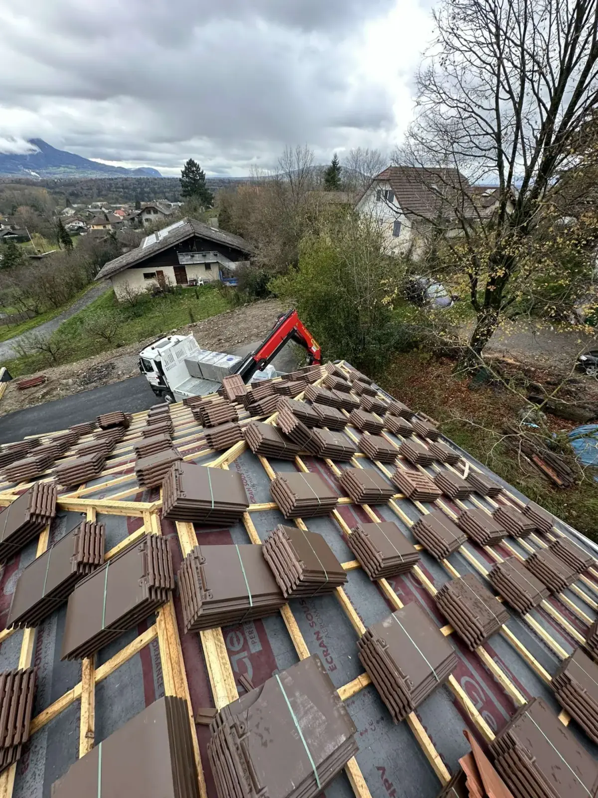 Chantier de couverture DCK BATIPRO : tuiles neuves montées sur le toit par camion-grue